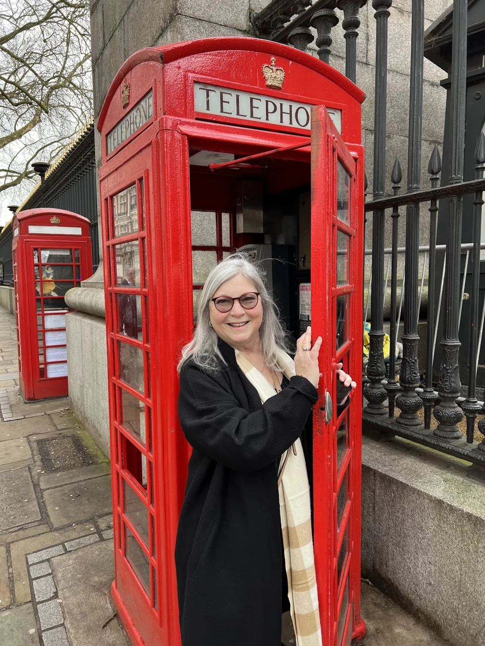 Phyllis Okon smiling beside a red telephone booth in London